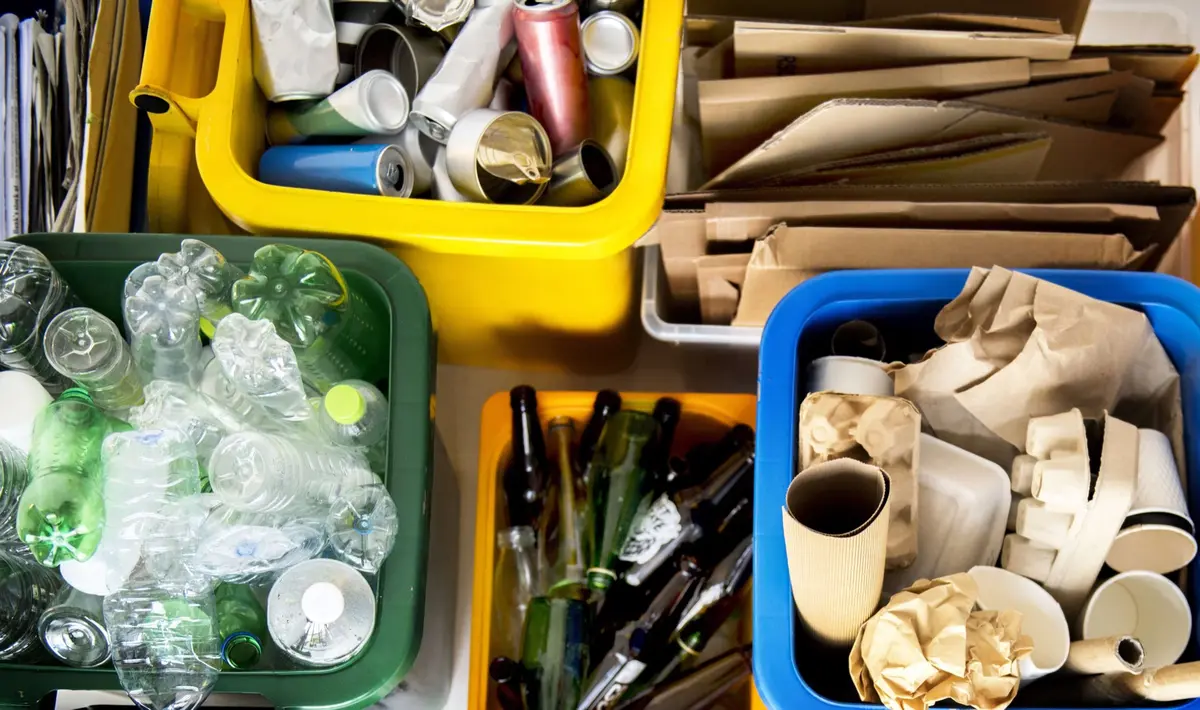 Recycling bins holding plastic bottles, glass, cans and paper cups